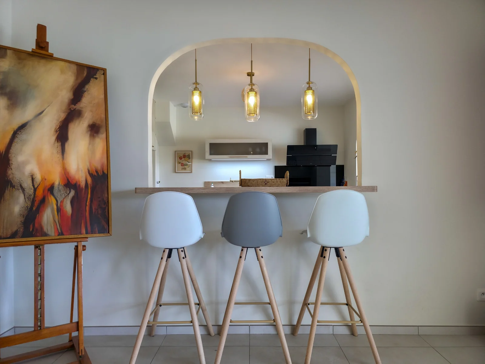 Comptoir avec tabourets sous une arche et suspensions